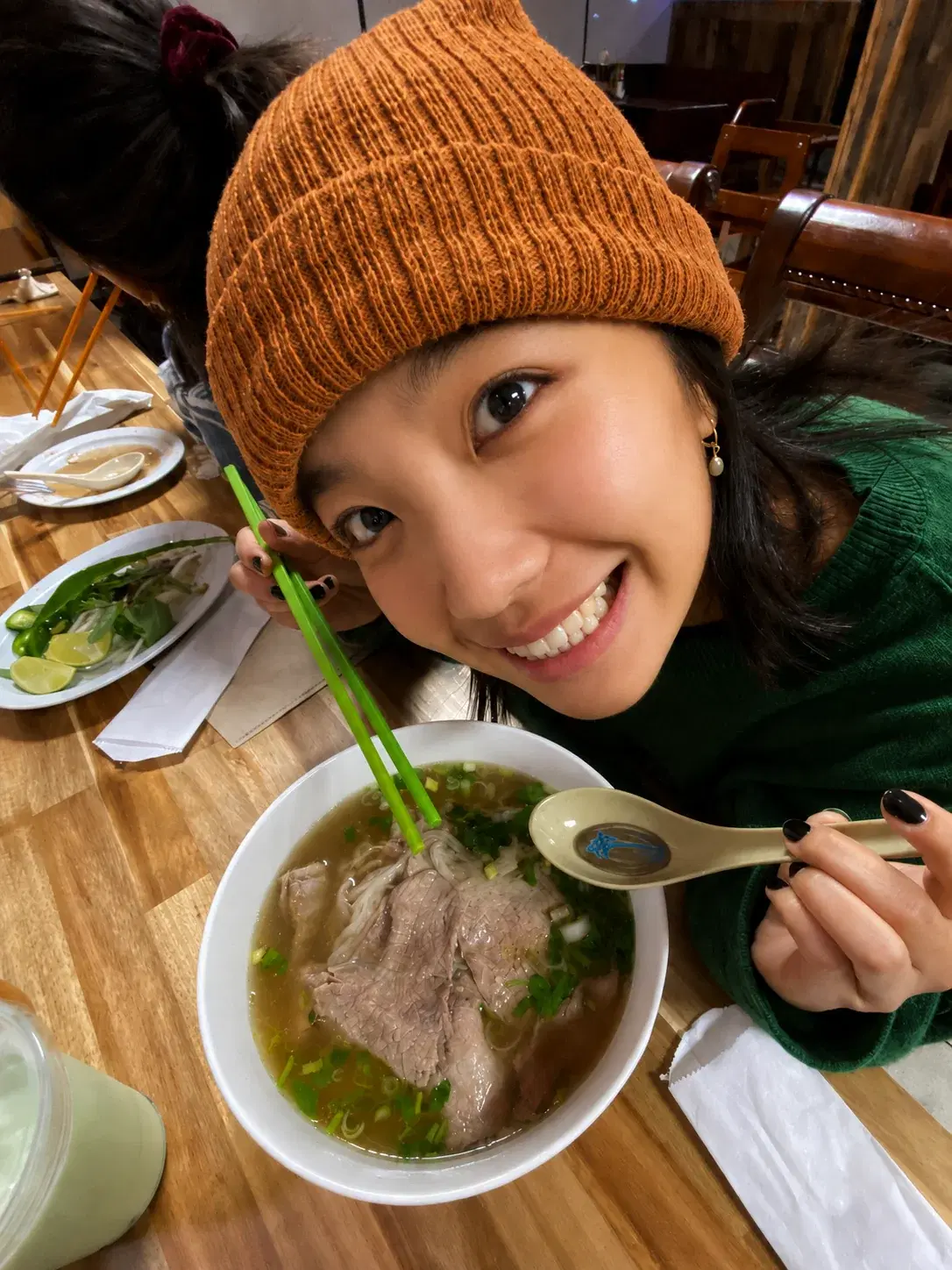 Cô gái cười tươi bên tô phở nóng trong quán ăn